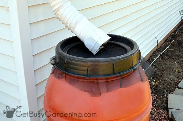 Flexible gutter tubing diverting water into a rain barrel