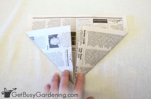 Folding the bottom corners of the newspaper
