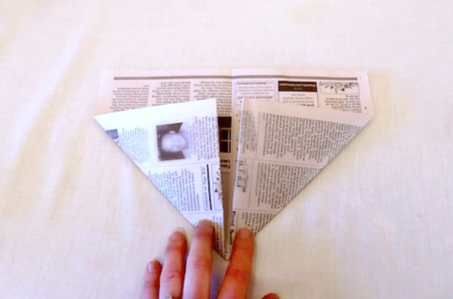Folding the bottom corners of the newspaper Folding the bottom corners of the newspaper
