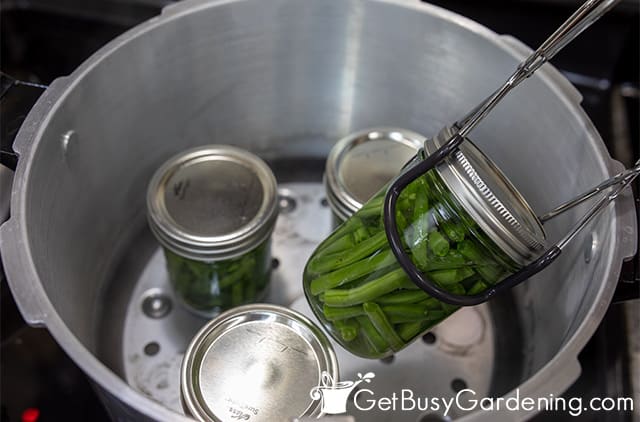 Removing a jar of green beans from the canner