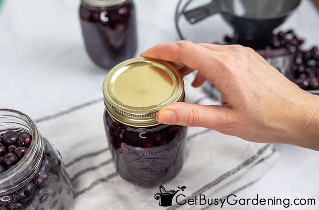 Tightening the bands and lids on jars of blueberries
