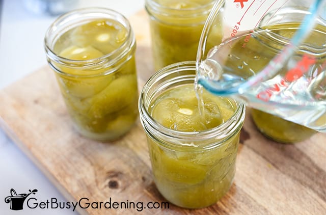 Pouring boiling water into jars of tomatillos